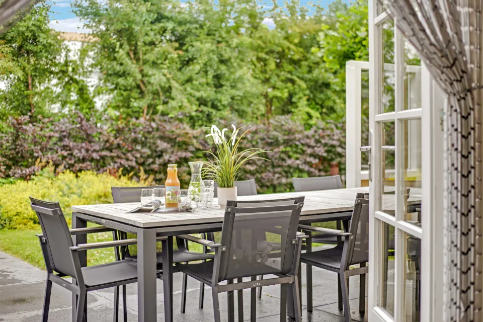 Terras met eettafel en stoelen gezien vanuit de openslaande deuren van de woning