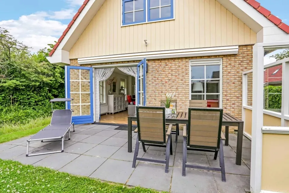 Vakantiewoning De Duinhaas 8 met terras, eettafel en een ligbed in de tuin