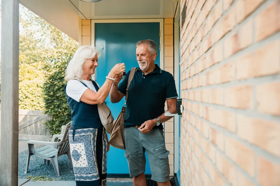 Ouder stel staat samen bij de blauwe voordeur van de vakantiewoning