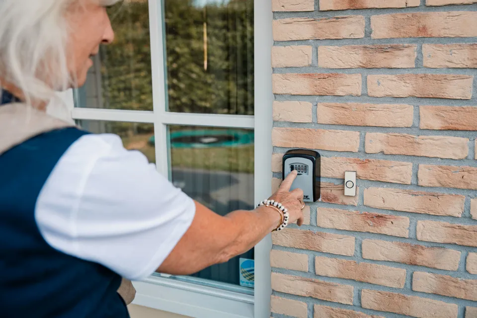 Gast opent de sleutelkluis aan de gevel naast de voordeur van de woning