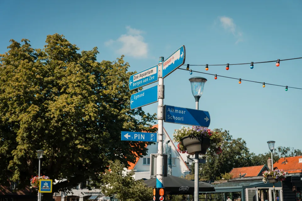 Blauwe wegwijzer met richtingborden en feestverlichting in het centrum