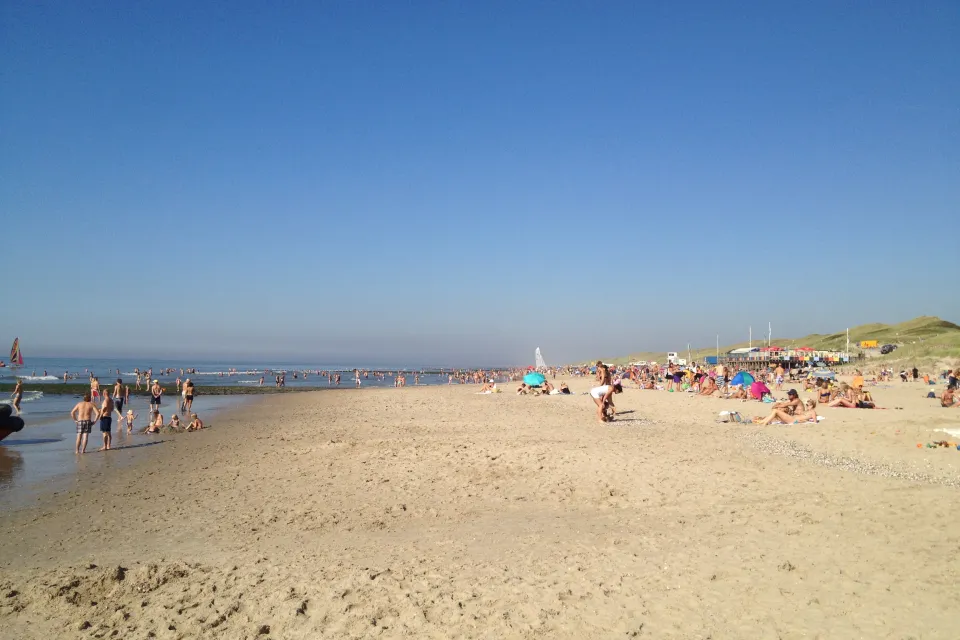 Breed zandstrand bij Schoorl aan Zee met badgasten en de duinenrij