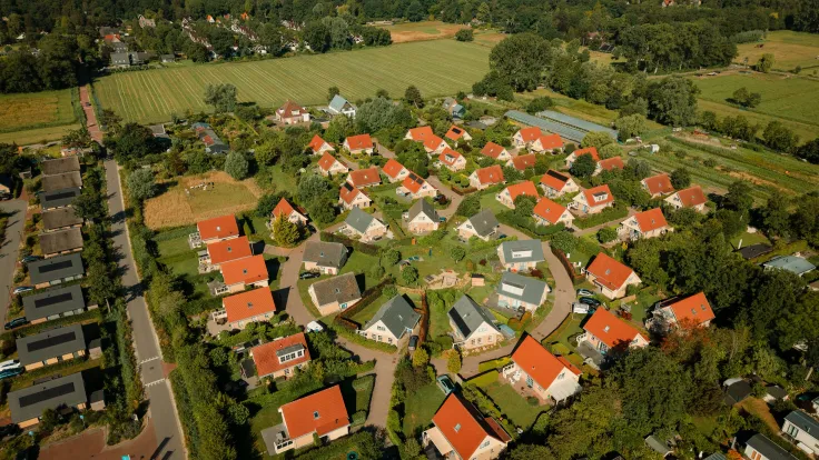 Luchtfoto van het vakantiepark met de woningen en het bos op de achtergrond