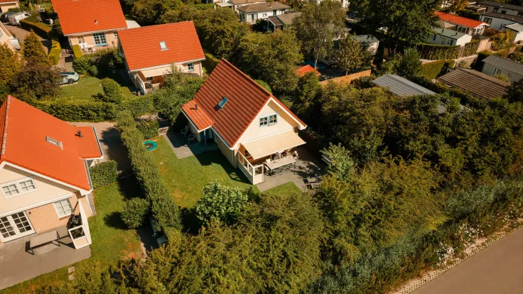 Luchtfoto van vakantiewoningen met rode daken en tuinen langs de laan